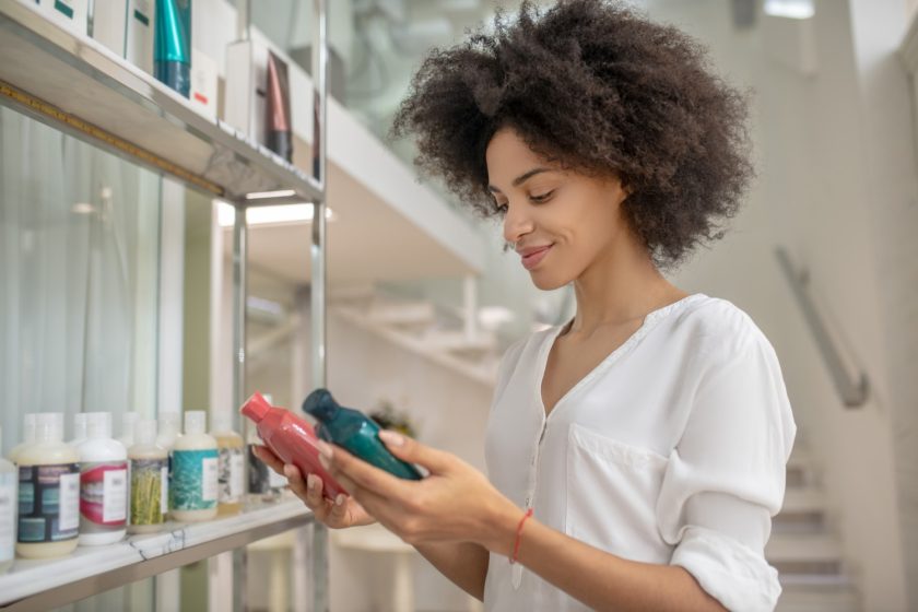 A imagem mostra uma mulher negra escolhendo produtos capilares para representar a Black Friday.